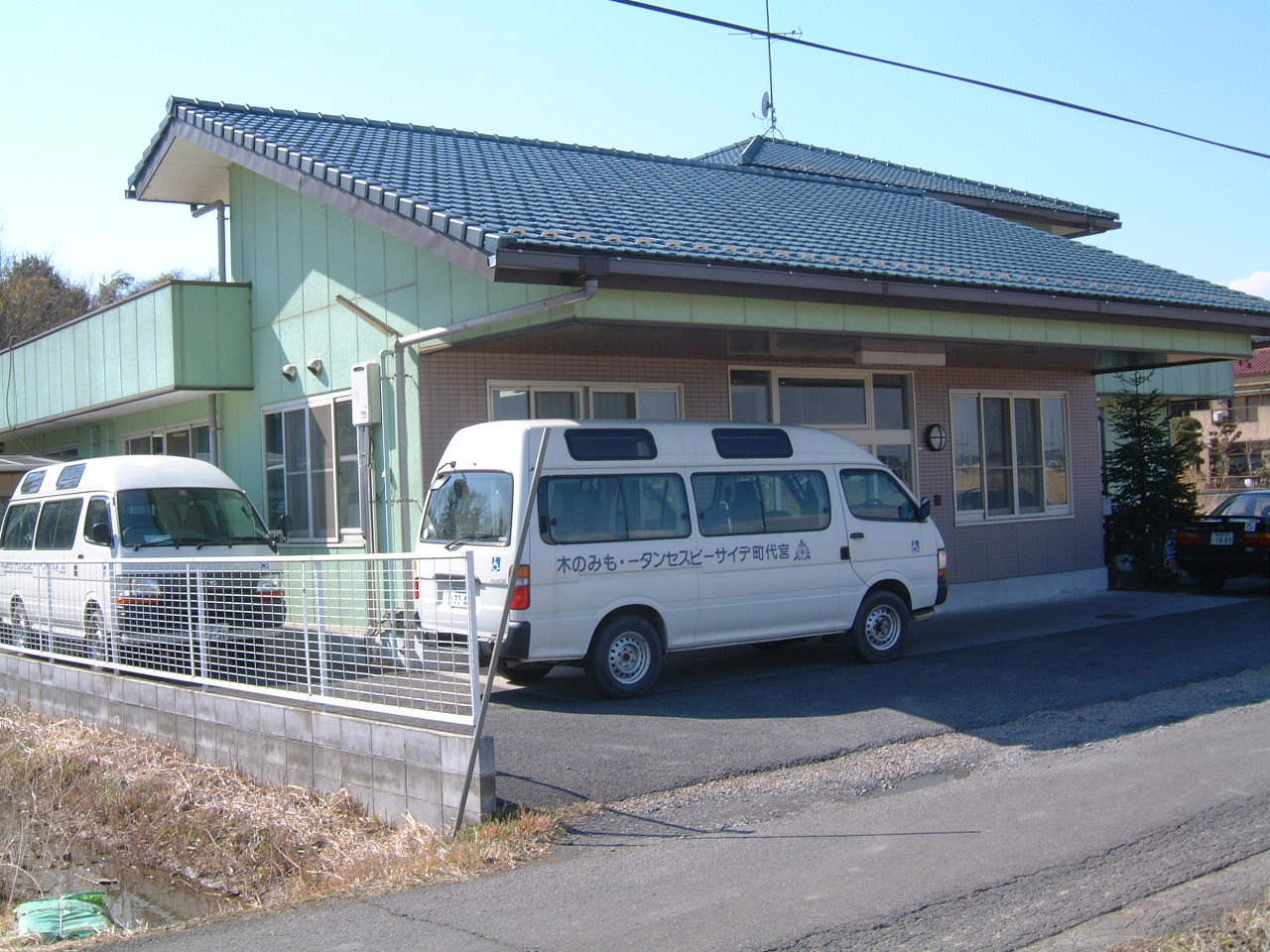 介護施設の建物外観と送迎用の福祉車両が駐車されている様子